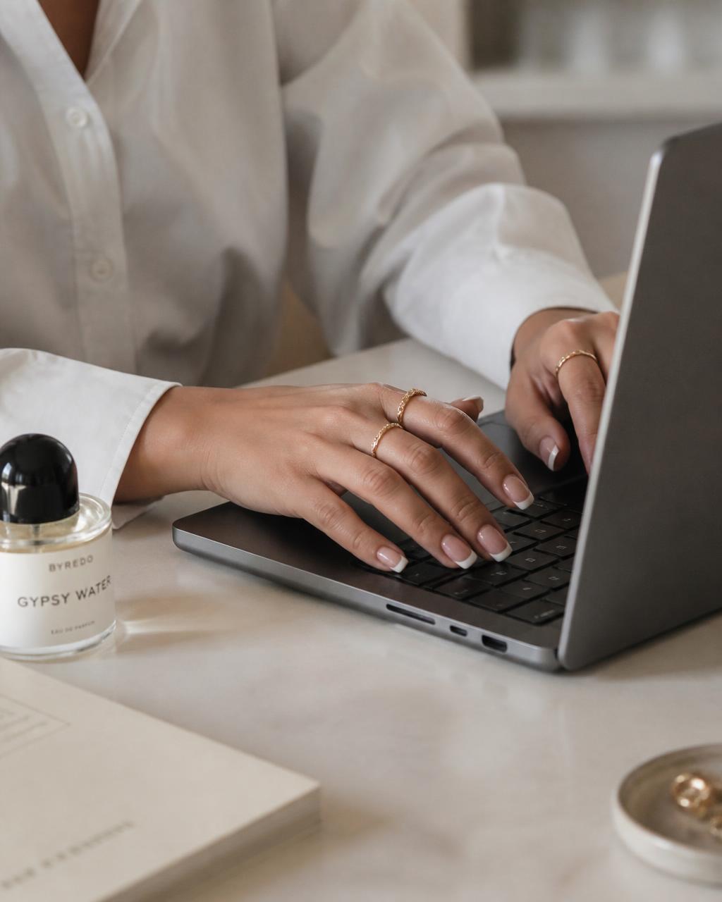 Hands with french tip nails typing on a laptop