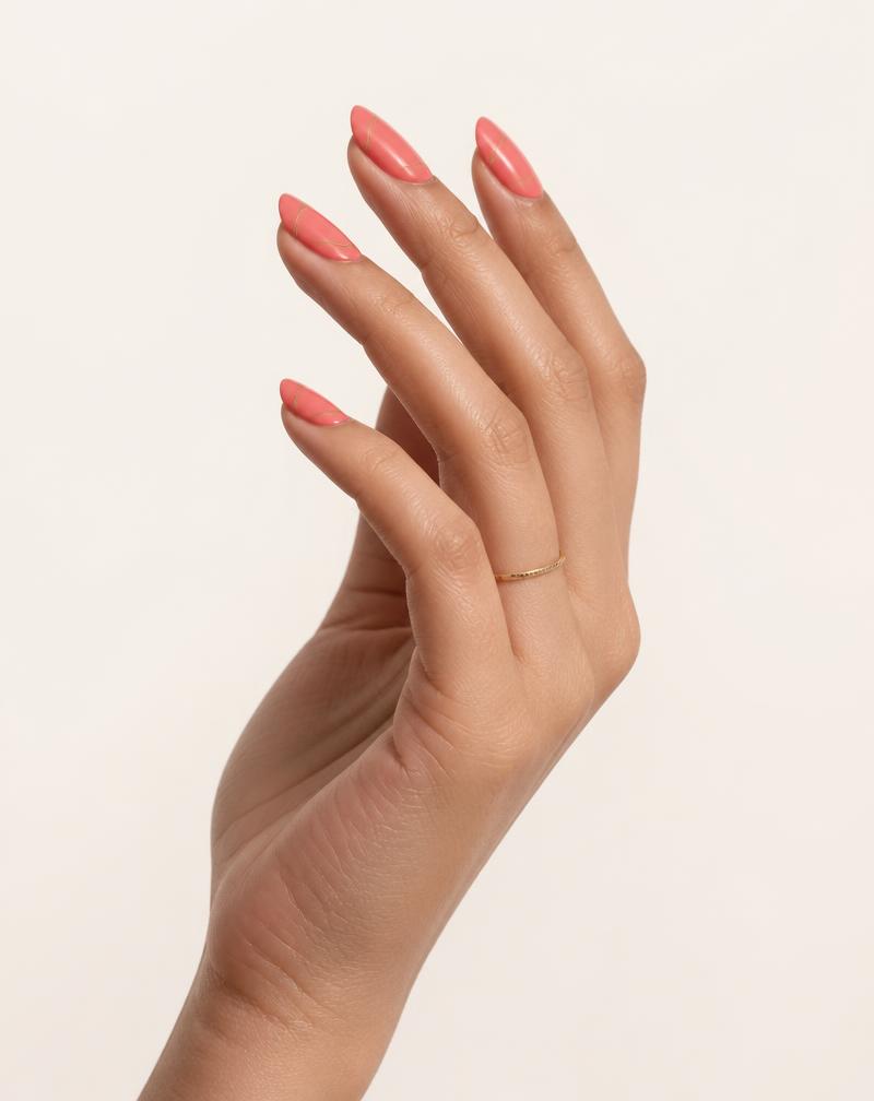 The same Make it NOD Coral Gloss press-on nail set worn on a light medium skin tone