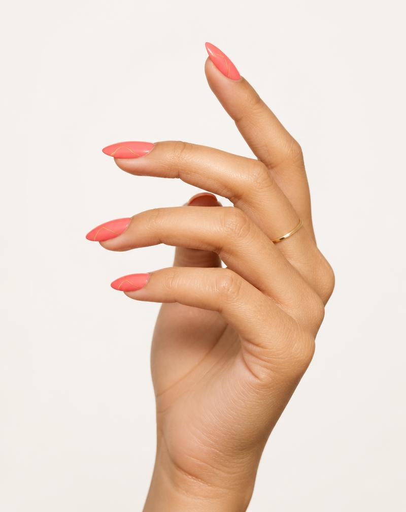 The same Make it NOD Coral Gloss press-on nail set worn on a medium skin tone